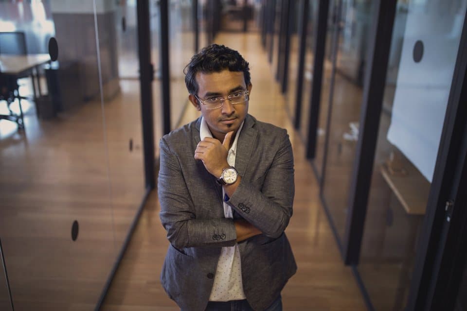 Professional standing in a glass-walled office corridor